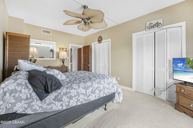 bedroom featuring multiple closets, ceiling fan, and light carpet