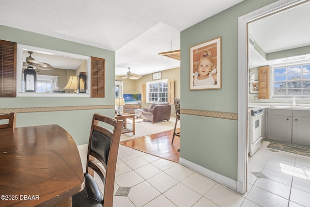 tiled dining area with sink, a textured ceiling, and ceiling fan