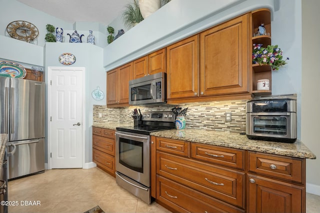 kitchen featuring light stone counters, light tile patterned floors, decorative backsplash, and appliances with stainless steel finishes