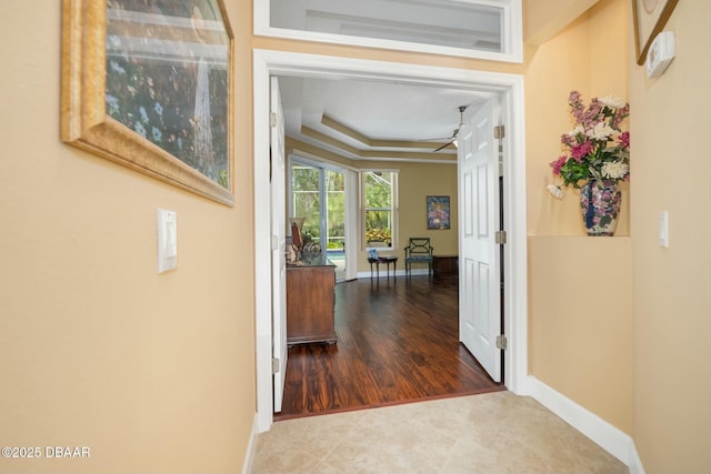 corridor featuring a raised ceiling and tile patterned floors