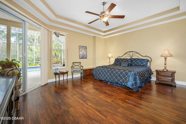 bedroom featuring hardwood / wood-style floors, access to exterior, ceiling fan, and a tray ceiling