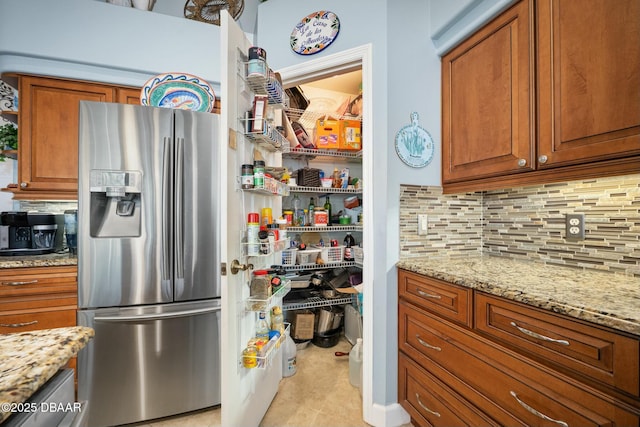 kitchen featuring backsplash, light stone counters, and stainless steel fridge with ice dispenser