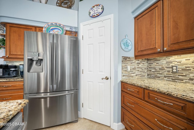 32 Gale Ln, Ormond Beach, FL 32174 - kitchen with stainless steel refrigerator with ice dispenser, brown cabinetry, decorative backsplash, and light stone countertops