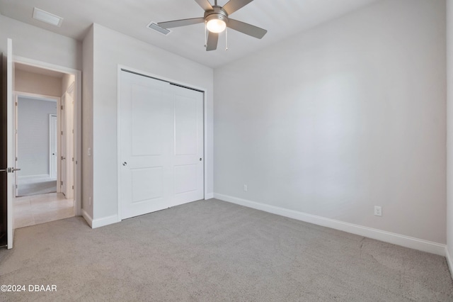 unfurnished bedroom featuring light carpet, ceiling fan, and a closet