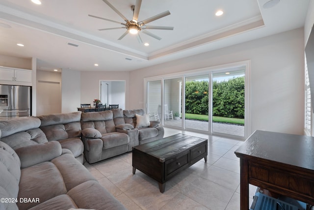 living room with ceiling fan, ornamental molding, light tile patterned floors, and a tray ceiling