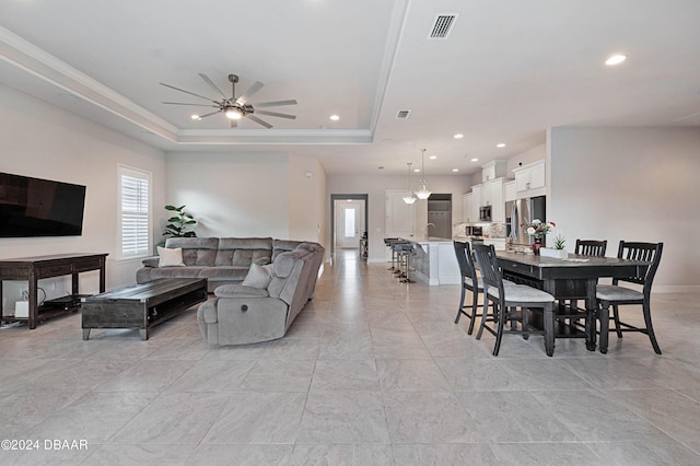 living room featuring ceiling fan, a raised ceiling, and sink