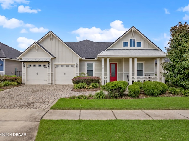 view of front of house featuring a front lawn, a garage, and covered porch