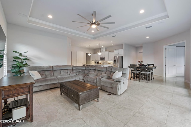 living room with ceiling fan and a raised ceiling