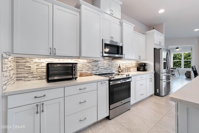 kitchen with white cabinets, decorative backsplash, ceiling fan, and stainless steel appliances