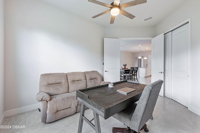 home office featuring light tile patterned flooring and ceiling fan with notable chandelier