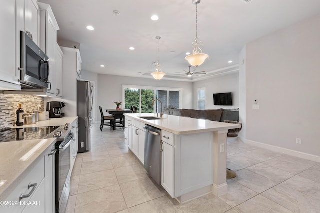 kitchen featuring a center island with sink, pendant lighting, sink, white cabinetry, and appliances with stainless steel finishes