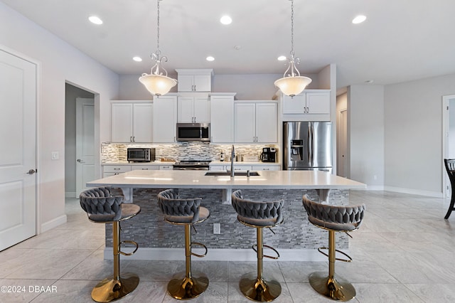 kitchen featuring white cabinets, appliances with stainless steel finishes, sink, and a kitchen island with sink