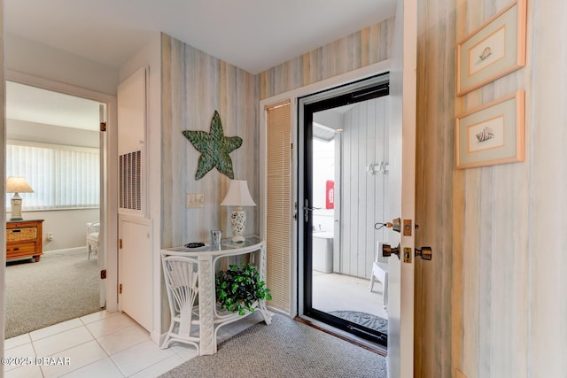 doorway with wallpapered walls, a healthy amount of sunlight, light tile patterned flooring, and light colored carpet