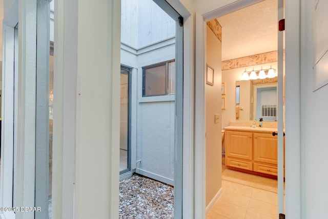 bathroom featuring baseboards, vanity, a textured ceiling, and tile patterned floors