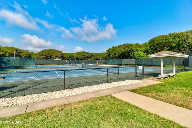 view of tennis court featuring a yard and fence