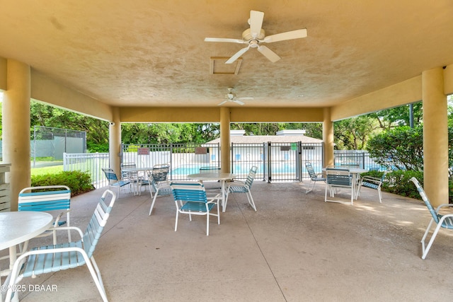 view of patio with fence, a ceiling fan, and a community pool