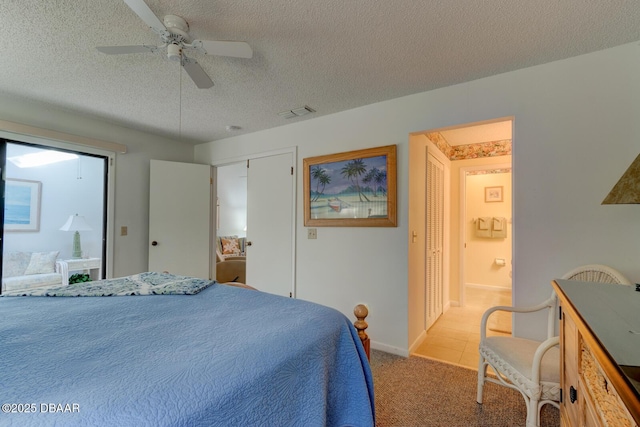 bedroom featuring a textured ceiling, ceiling fan, carpet floors, visible vents, and ensuite bath