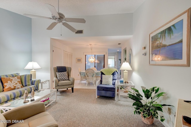 living room featuring carpet floors, visible vents, a textured ceiling, and ceiling fan with notable chandelier