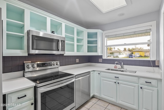 kitchen featuring white cabinetry, sink, tasteful backsplash, light tile patterned floors, and appliances with stainless steel finishes