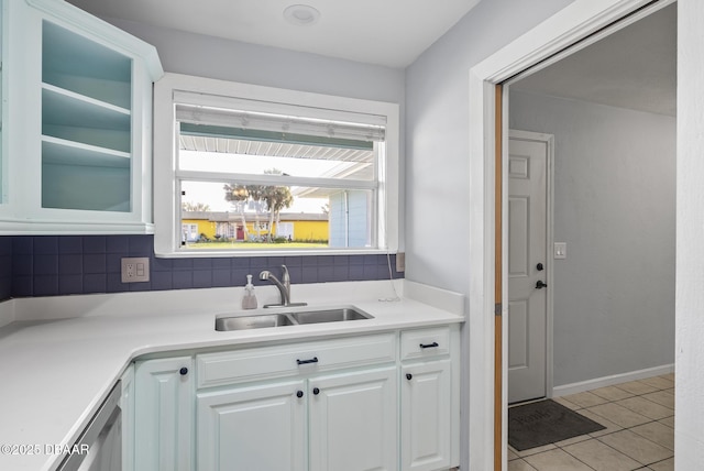 kitchen featuring white cabinets, light tile patterned floors, backsplash, and sink