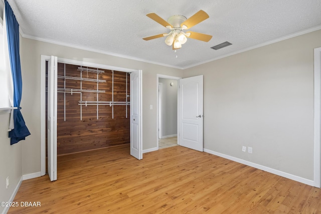 unfurnished bedroom featuring ceiling fan, crown molding, a textured ceiling, a closet, and light wood-type flooring