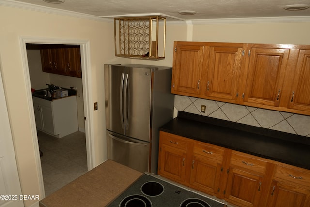 829 N Beach St, Ormond Beach, FL 32174 - kitchen featuring freestanding refrigerator, brown cabinetry, dark countertops, and ornamental molding
