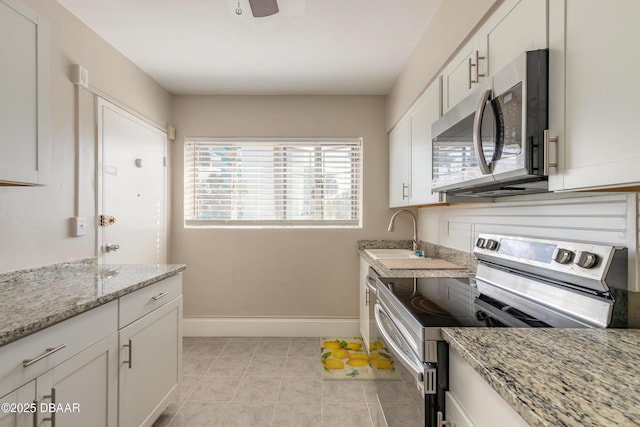 kitchen with white cabinets, light tile patterned floors, baseboards, and stainless steel appliances