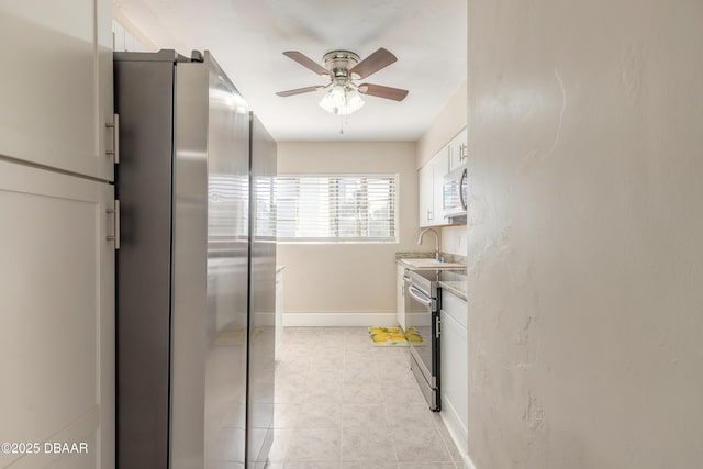 kitchen with baseboards, ceiling fan, appliances with stainless steel finishes, light countertops, and white cabinetry