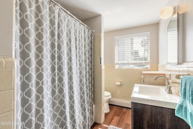 bathroom with a wainscoted wall, tile walls, toilet, vanity, and wood finished floors