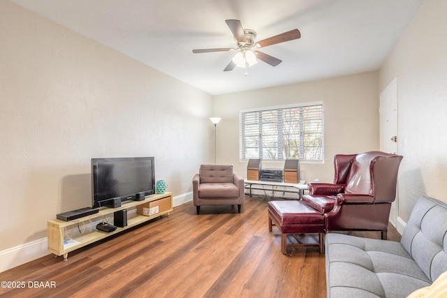 living room with a ceiling fan, baseboards, and wood finished floors