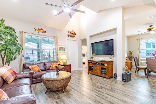 living room with high vaulted ceiling, light wood-type flooring, ceiling fan, and plenty of natural light