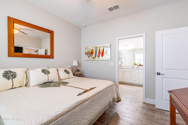 bedroom featuring wood-type flooring, a textured ceiling, and connected bathroom