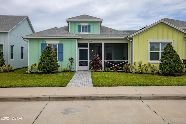 view of front of house with a front lawn and a sunroom