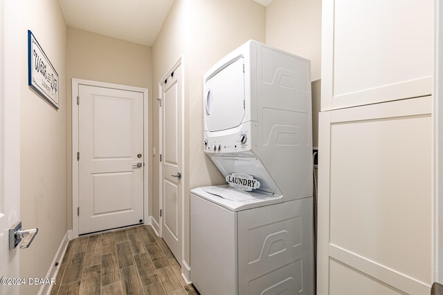 washroom with stacked washer / drying machine and dark wood-type flooring