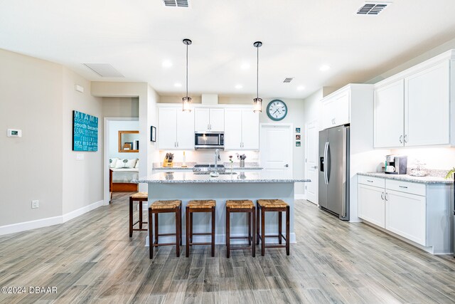 kitchen featuring white cabinetry, decorative light fixtures, light stone counters, and stainless steel appliances