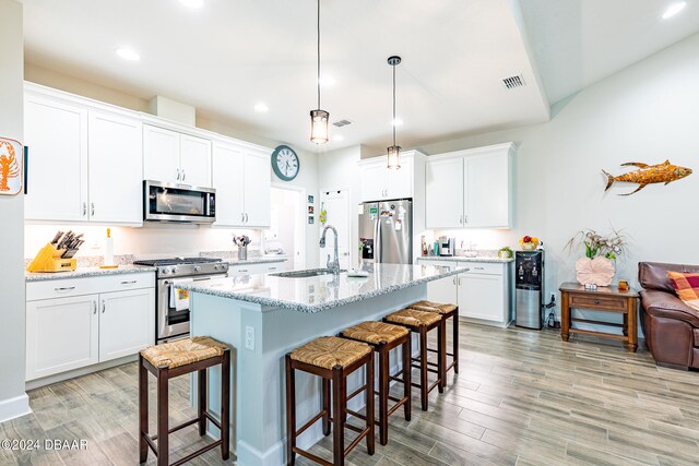 kitchen with stainless steel appliances, white cabinets, sink, and light hardwood / wood-style flooring