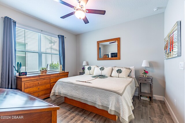 bedroom featuring dark wood-type flooring, ceiling fan, and a textured ceiling