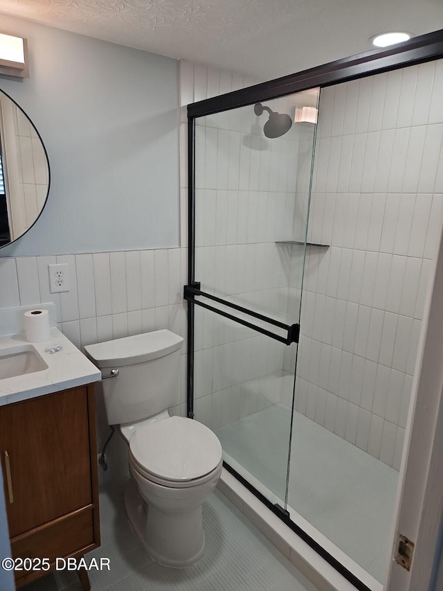 bathroom with tile walls, toilet, tiled shower, tile patterned floors, and a textured ceiling