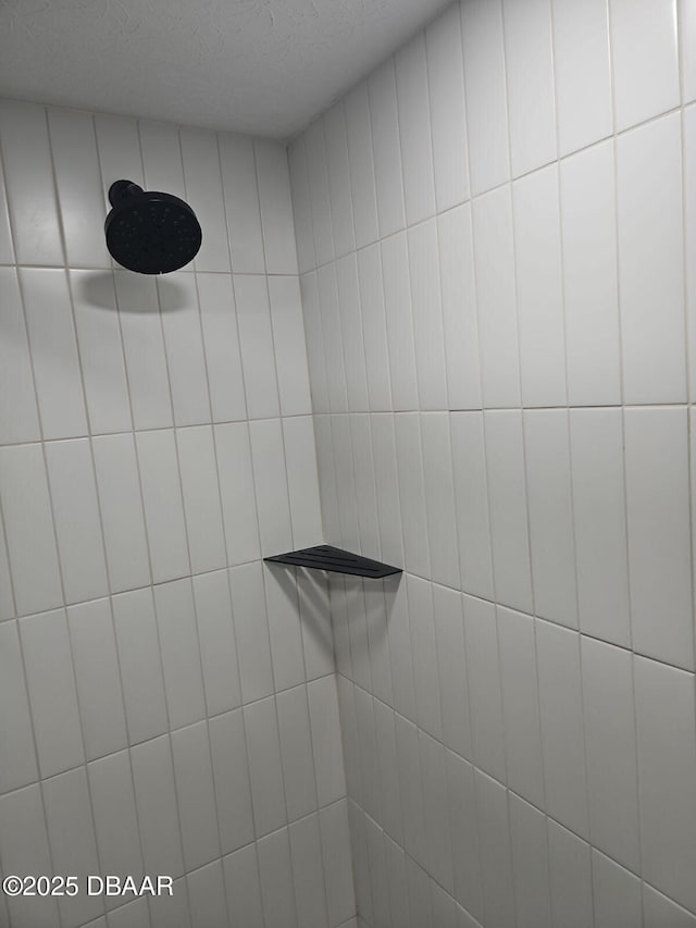 interior details with a tile shower and a textured ceiling