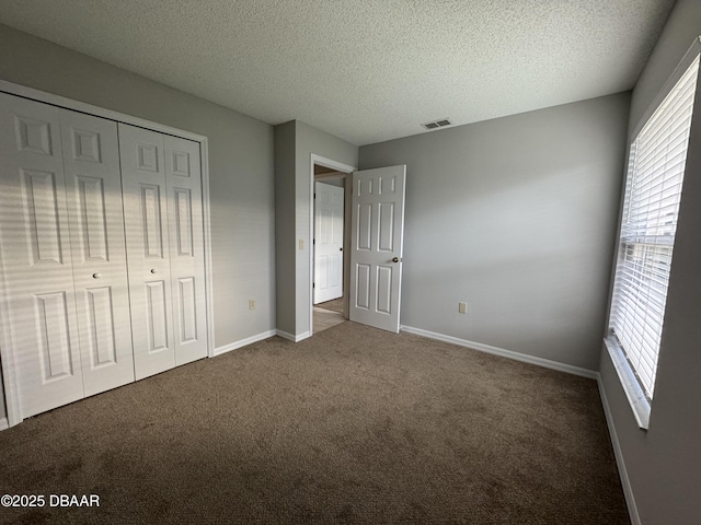 unfurnished bedroom featuring a closet, a textured ceiling, and dark colored carpet