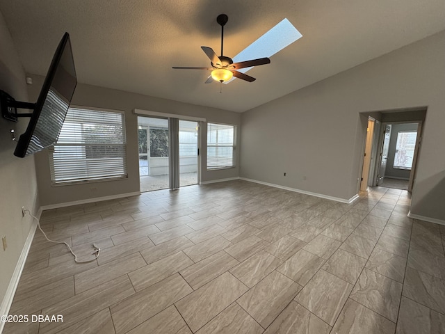 empty room featuring plenty of natural light, ceiling fan, a textured ceiling, and vaulted ceiling