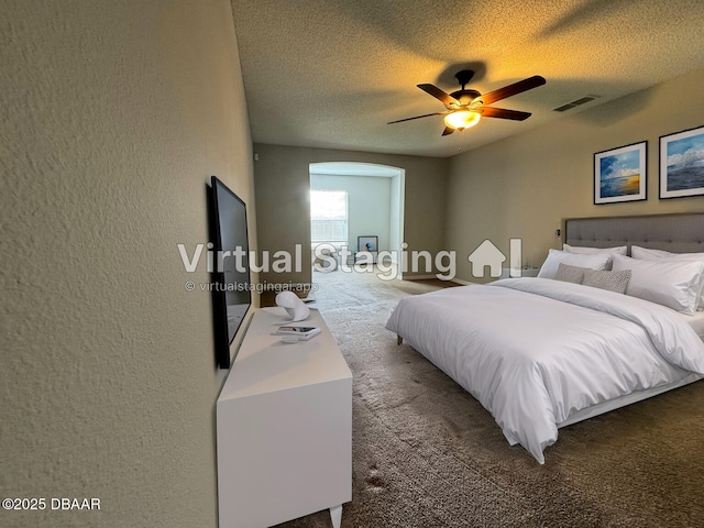 bedroom with ceiling fan, dark carpet, and a textured ceiling