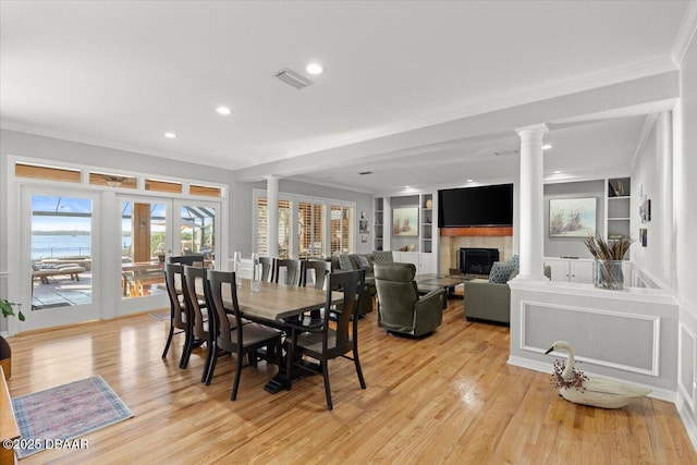 dining area with crown molding, built in features, and decorative columns