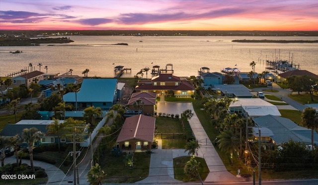 aerial view at dusk featuring a water view