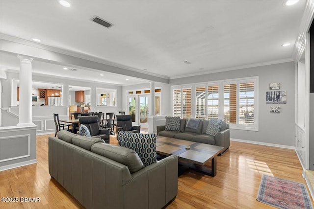 living room featuring decorative columns, light hardwood / wood-style flooring, and ornamental molding