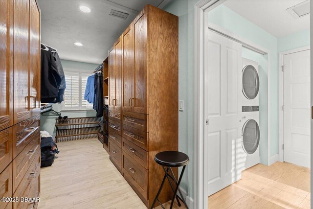 laundry room with light hardwood / wood-style floors and stacked washer and clothes dryer