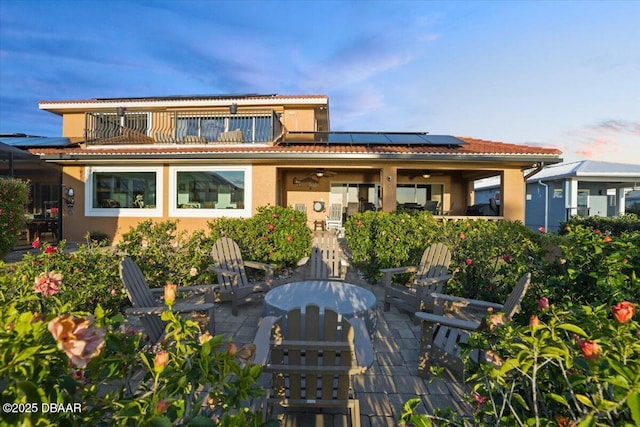 rear view of property with solar panels and a patio