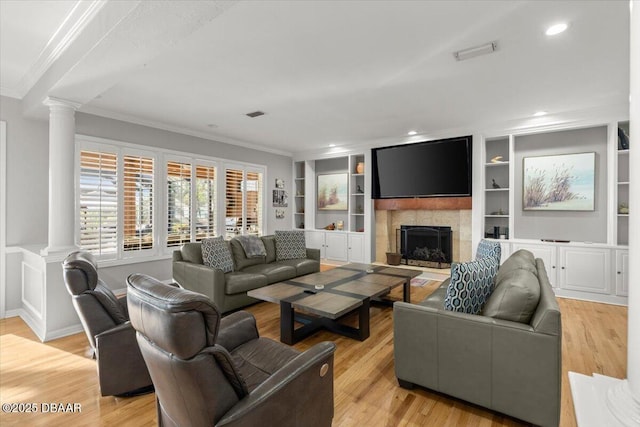 living room with built in shelves, ornate columns, a fireplace, light hardwood / wood-style floors, and crown molding