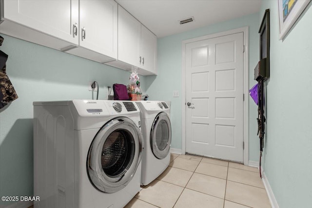 laundry area featuring light tile patterned floors, separate washer and dryer, and cabinets