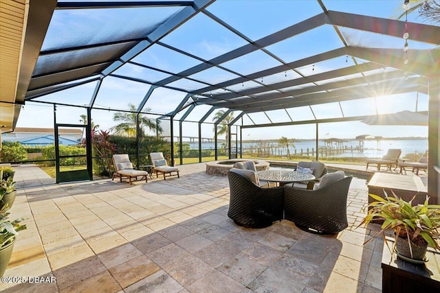 view of patio with a lanai and a water view